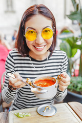 A woman eats a traditional Hungarian goulash or tomato soup from a saucepan in an outdoor restaurant
