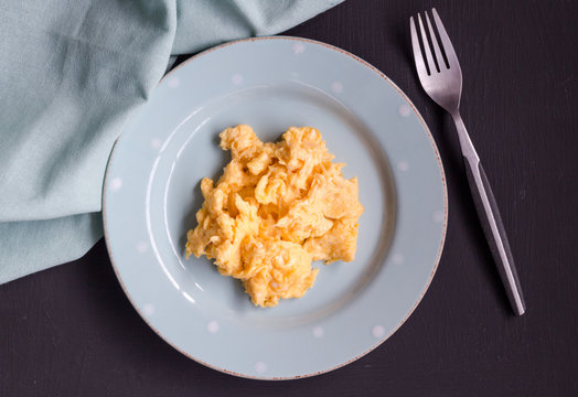 Scrambled eggs in plate on black table close up