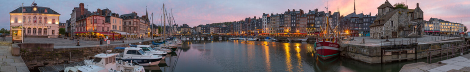 Fototapeta na wymiar Panoramic view at dusk of the beautiful Honfleur harbour, which offers many fine restaurants overlooking the water