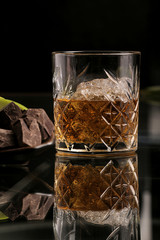 Whiskey on black background with chocolate pieces and apple  slices
