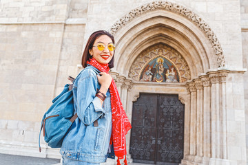 tourist asian woman with backpack near historical architecture of a catholic church, sightseeing...
