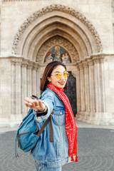 Fototapeta na wymiar Follow me to Matthias church in Budapest. Mixed race woman traveler with backpack heading to tourist sights and destinations in Europe