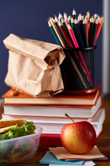 Concept of school lunch break with healthy lunch box and school supplies on white desk, selective focus.