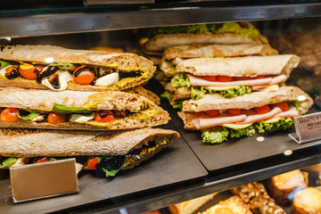 sandwiches stuffed with ham and tomato for sale in a bakery shop