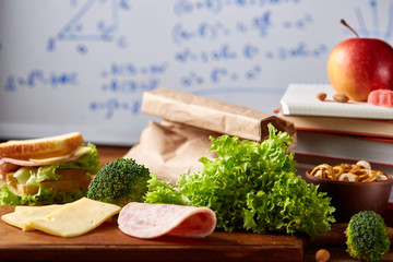 Preparing ham sandwiches for school lunchbox on wooden background, close up.