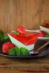 Two layered dessert panna cotta with matcha tea and strawberry jelly in a square bowl