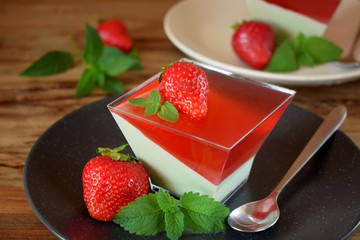 Two layered dessert panna cotta with matcha tea and strawberry jelly in a square bowl