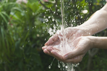 closeup water flow to hand of women for nature concept on the garden background.