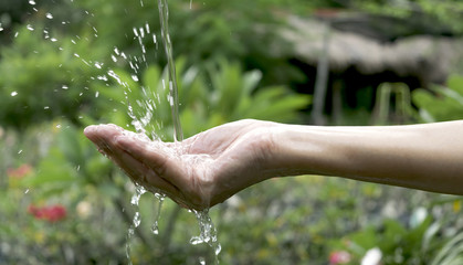 closeup water flow to hand of women for nature concept on the garden background.