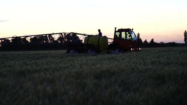 Worker serves a machine for spraying pesticides and herbicides on an agricultural field at night. 4K video