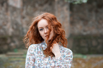 Portrait of a young red-haired curly girl with freckles