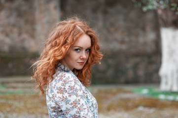 Portrait of a young red-haired curly girl with freckles