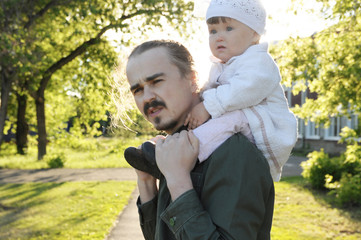 father with daughter baby on shoulders walking in park at sunny day. Family authentic lifestyle portrait