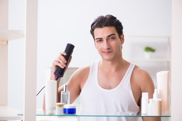 Young man drygin his hair in the morning