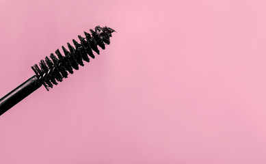 Black mascara brush on pink background