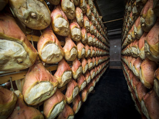 Thighs of ham during the seasoning process hanging in a cellar.