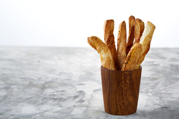 Delicious breadsticks grissini on grey kitchen table in wooden oldstyle cup, close-up, selective focus
