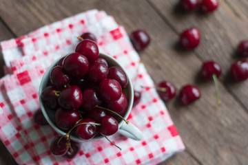 ripe juicy cherries in Cup on wooden background