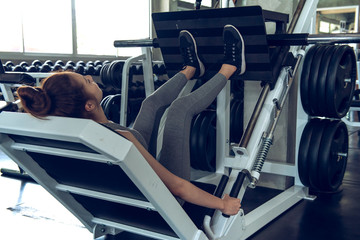 Portrait sport girl doing leg presses in the gym with smiling face, fitness and exercise concept.
