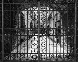 Hand-worked wrought iron gate with internal courtyard of an old Italian palace.