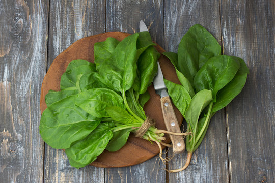 Bunch of fresh spinach with roots on a cutting board with a knife. on a wooden table. rustic style