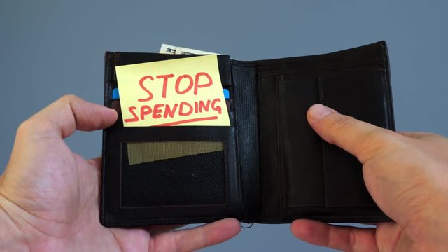 Man opens wallet with memo Stop spending. Wasting money concept.