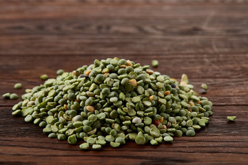 Pile of green peas on rustic wooden background, close-up, top view, selective focus.