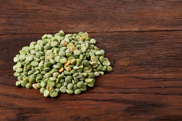 Pile of green peas on rustic wooden background, close-up, top view, selective focus.