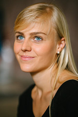 Fototapeta premium Close-up portrait head shot of a young and attractive blond woman with blue eyes. She is casually and comfortably dressed and is smiling as she looks off camera. 
