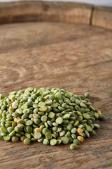 Pile of green peas on the top of wooden barrel, close-up, top view, selective focus.