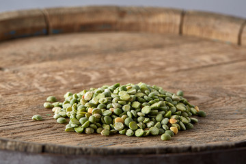 Pile of green peas on the top of wooden barrel, close-up, top view, selective focus.