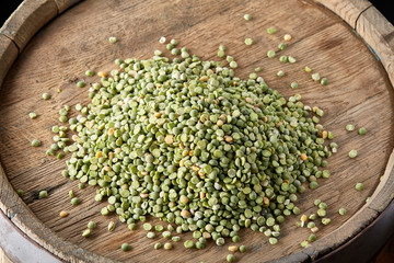Pile of green peas on the top of wooden barrel, close-up, top view, selective focus.