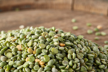 Pile of green peas on the top of wooden barrel, close-up, top view, selective focus.