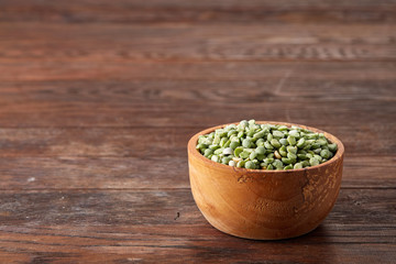 Raw green peas on a wooden plate over rustic background, close-up, selective focus, shallow depth of field.