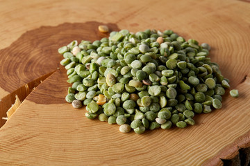 Pile of green peas on a wooden log, close-up, top view, selective focus.