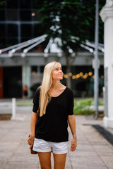 An image of a pretty blonde girl walking outside of an old colonial building on a sunny day.  She is wearing a comfortable clothes and she enjoys looking around the place.