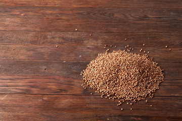 Buckwheat groats on wooden background, top view, close-up, selective focus.