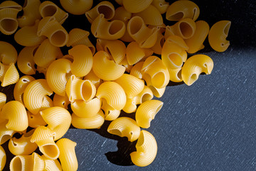 Close up of a raw dry Italian pasta horns on a black board.
