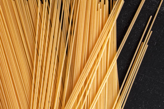 Close up of a raw dry Italian pasta spaghetti on a black board