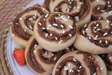 Chocolate rolls on a plate with fresh strawberries on wooden table