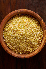 Lentils in a wooden bowl on rustic wooden background, top view, close-up, selective focus.