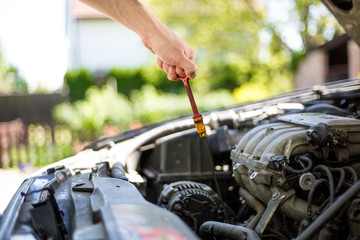 Fototapeta premium Young man hands checking the oil in the car, regular maintenance