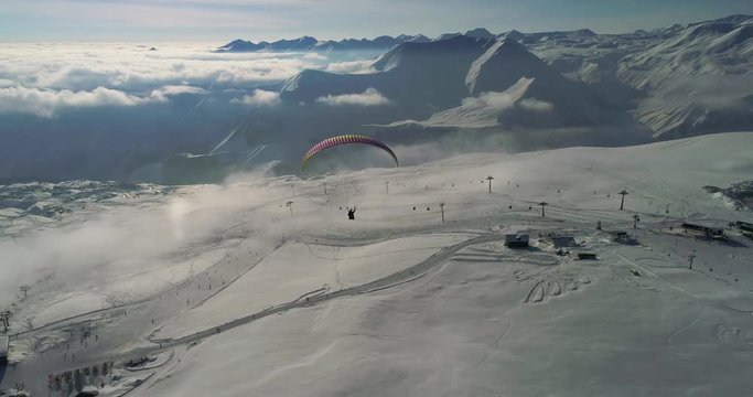 Amazing aerial video of paraplane at snow mountains. Close-up drone of paraglide winter's mountains