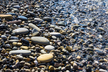 sea pebble beach with multicoloured stones, waves with foam