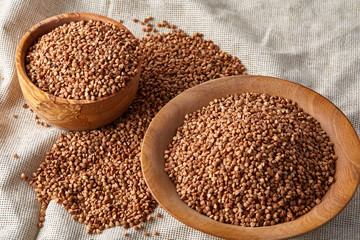Bowl full of buckwheat grains on rustic wooden table, close-up, selective focus, shallow depth of field.