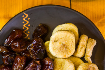 dried dates and figs in a ceramic plate on a wooden table