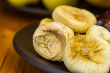 dried dates and figs in a ceramic plate on a wooden table