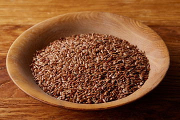 Bowl full of buckwheat grains on rustic wooden table, close-up, selective focus, shallow depth of field.