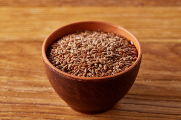 Bowl full of buckwheat grains on rustic wooden table, close-up, selective focus, shallow depth of field.