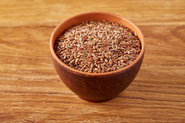 Bowl full of buckwheat grains on rustic wooden table, close-up, selective focus, shallow depth of field.